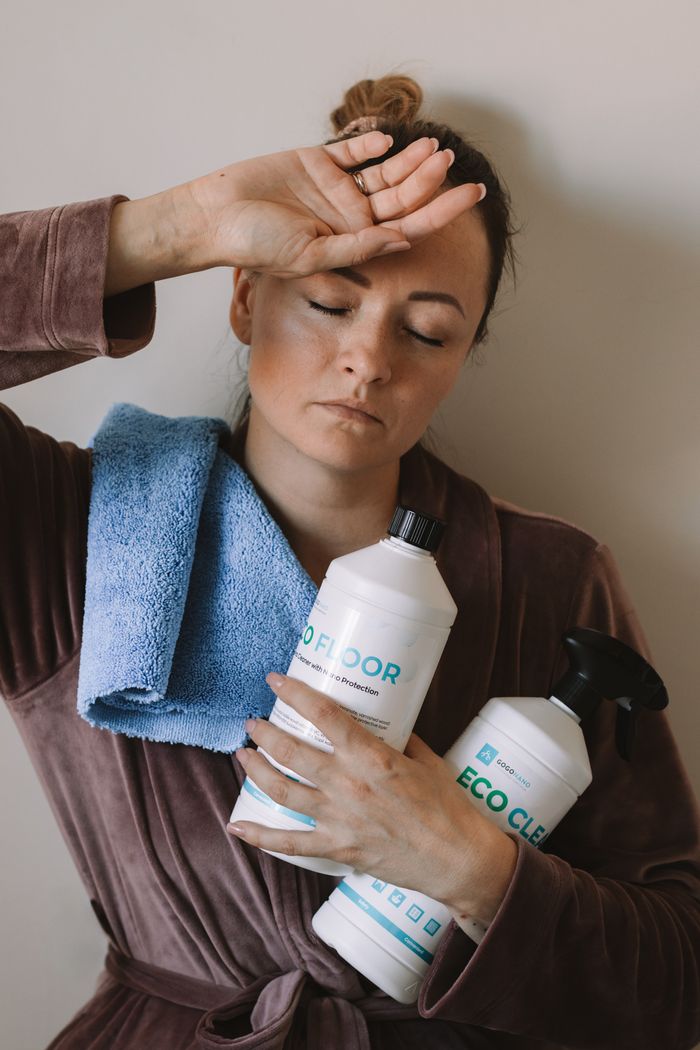 project-03-b Woman holding eco-friendly cleaning products with blue microfiber cloth indoors.